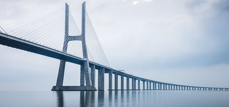 Die Vasco da Gama-Brücke spannt sich bei Sonnenaufgang über das Meer.