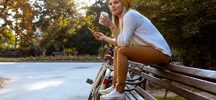 Junge Frau mit Smartphone auf Bank