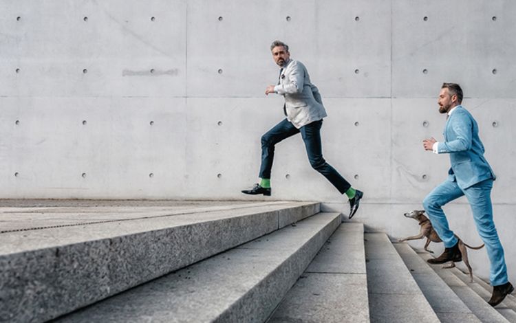 Zwei Manager rennen eine Treppe hinauf