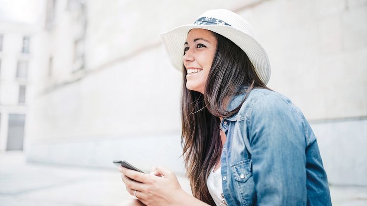 Junge Frau mit Hut und Smartphone