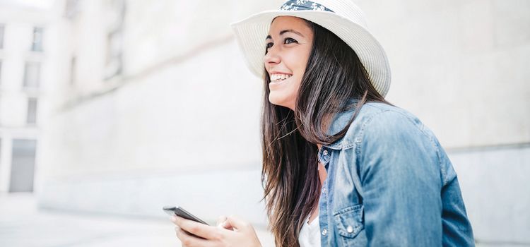 Junge Frau mit Hut und Smartphone