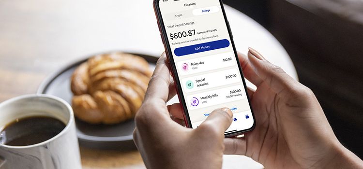 Eine Frau hält ein Smartphone in der Hand und bedient die neue App von PayPal