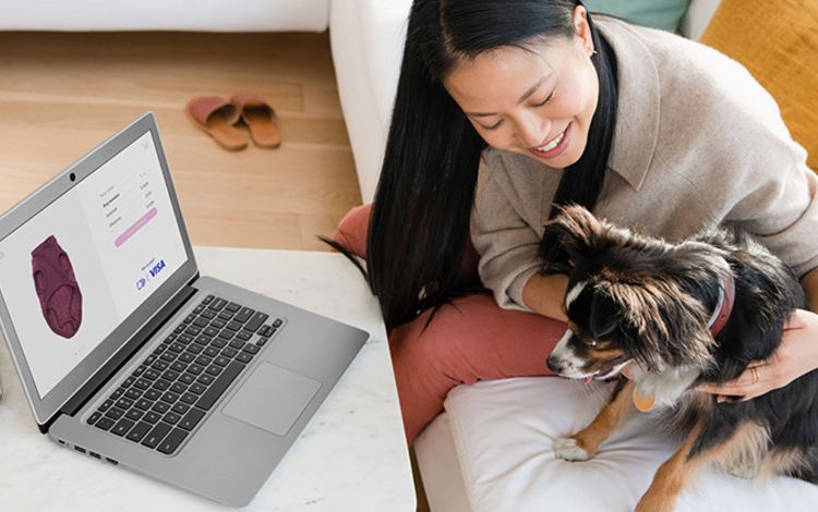 Junge Frau mit Hund auf Sofa beim Online-Shoppen