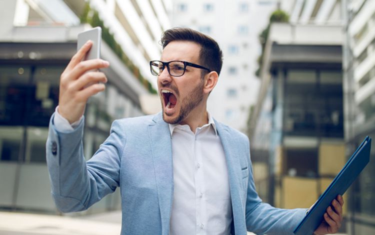 Junger Mann mit Smartphone ärgert sich