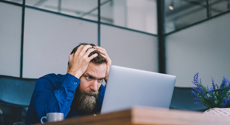 Junger Mann vor Laptop, der verzweifelt scheint