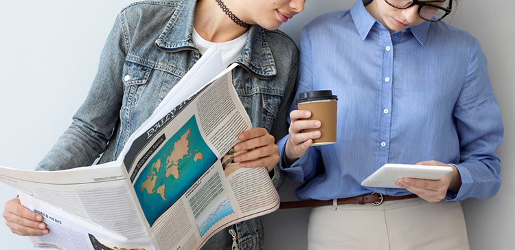 Zwei Frauen mit Zeitung und Tablet