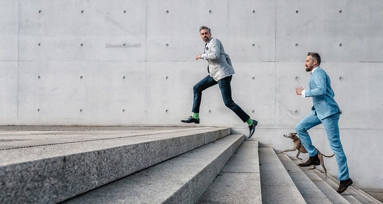 Zwei Manager rennen eine Treppe hinauf